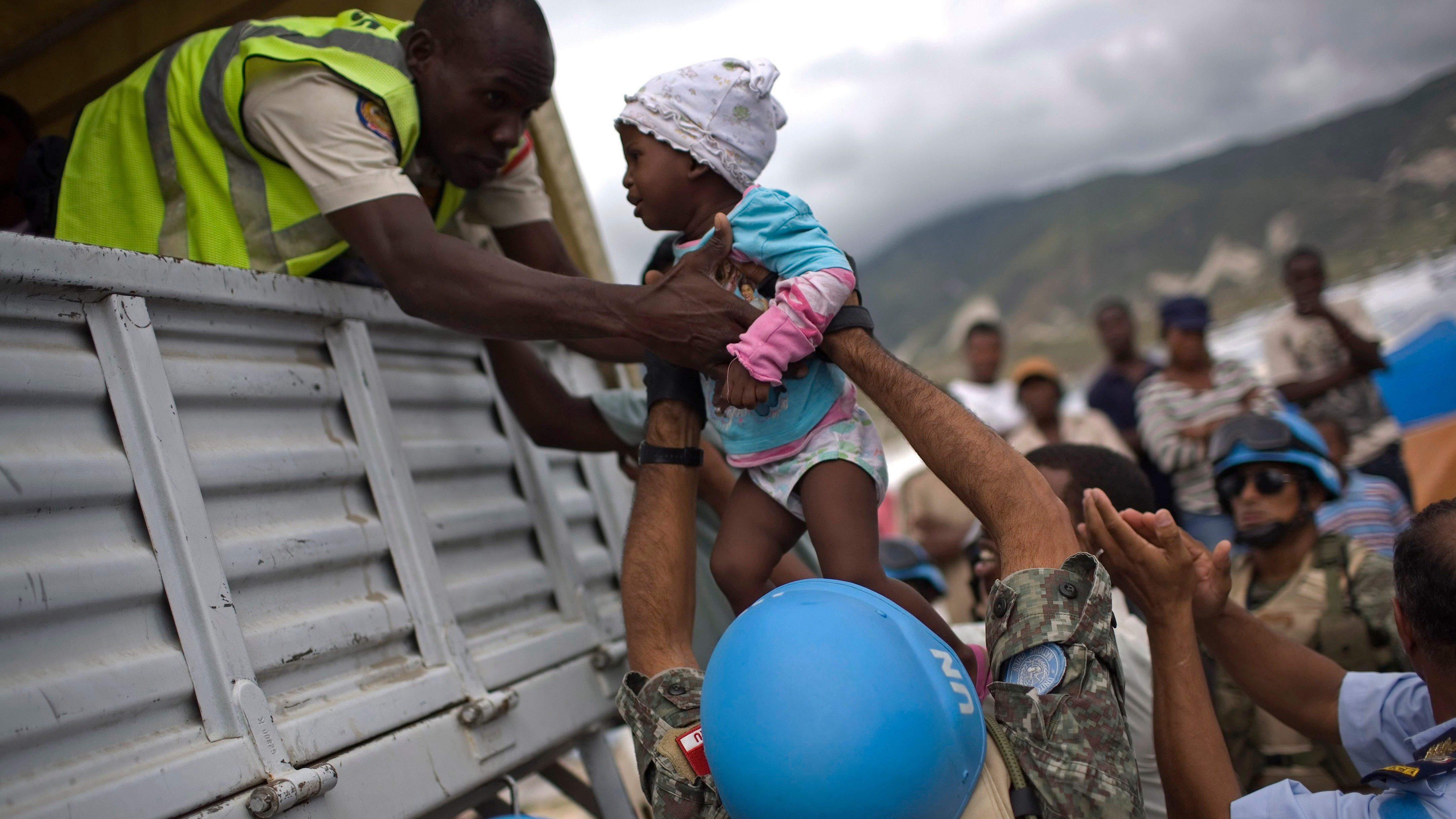 Záchranári evakuujú malé dieťa počas hurikánu Tomas na Haiti